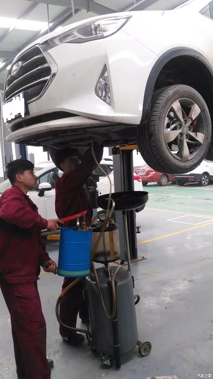 辛苦的师傅正在换机油,旁边的学徒学的很认真的