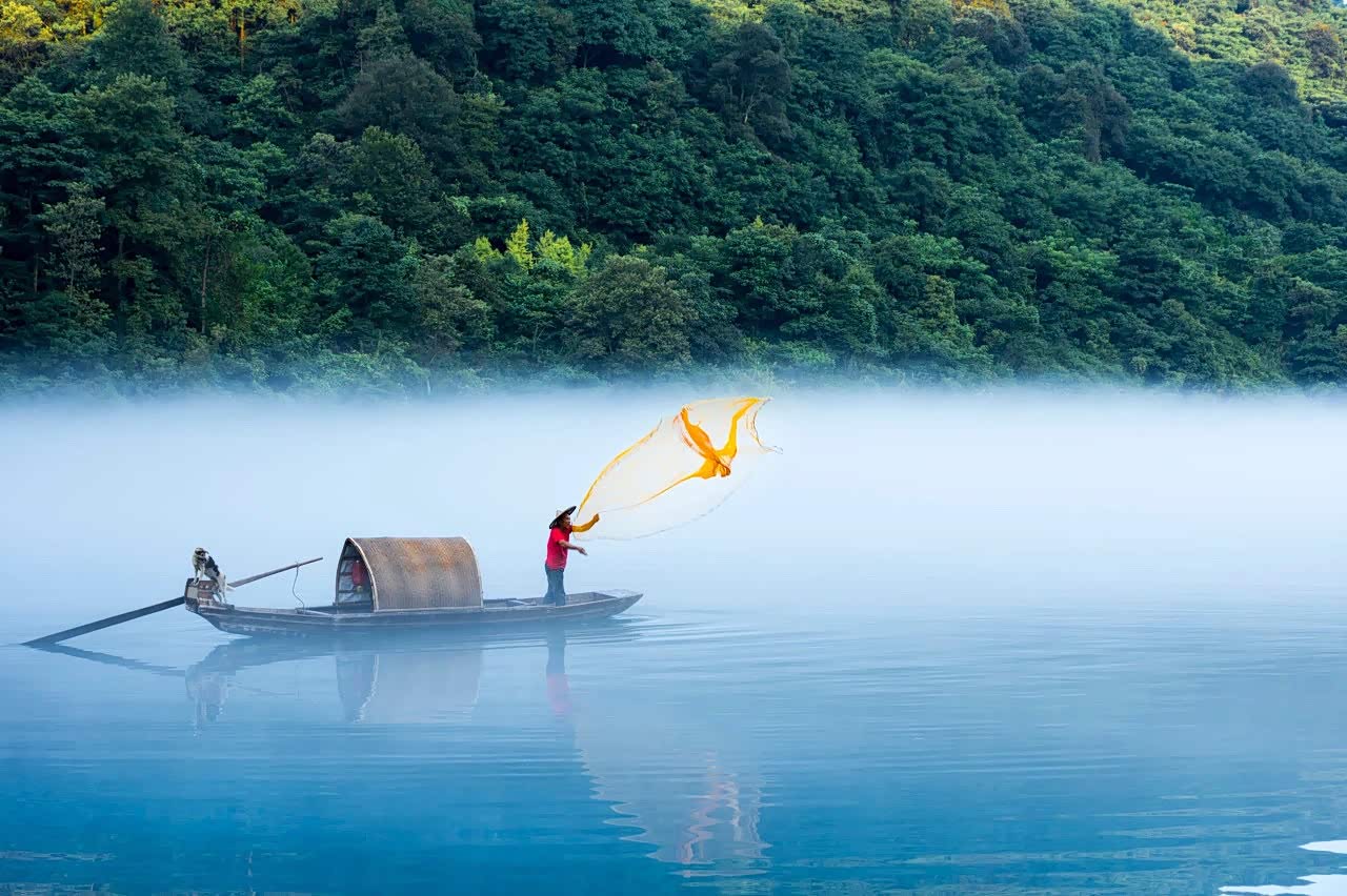 湖南小东江,云雾萦绕山间,一叶小舟飘在江面,静如止水