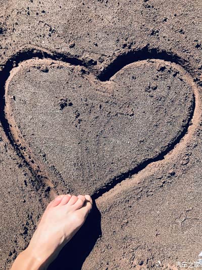 沙滩玩耍,用脚勾画出一个爱心的标志.