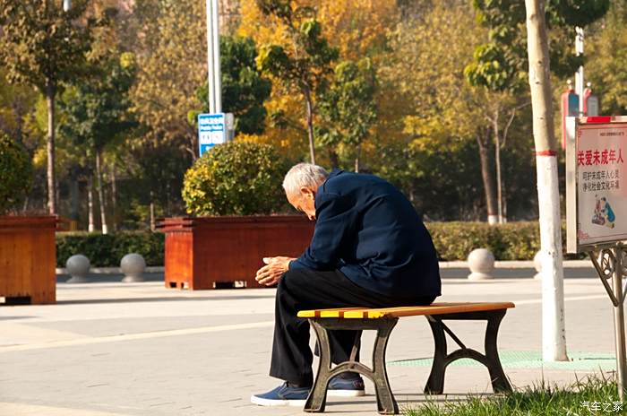 一位老人坐在长椅上静静的享受阳光温暖和秋的凄凉还有点应景