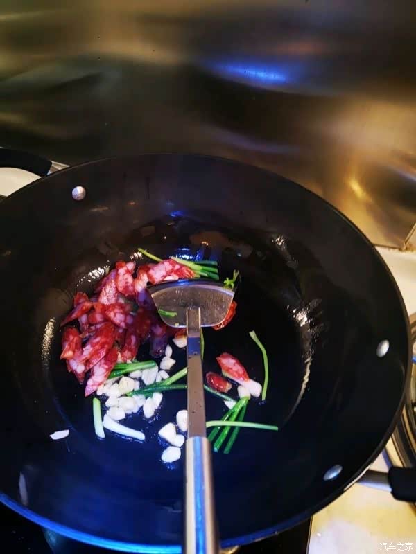 热锅,温度够了放油,放入蒜头和切片后的腊肠大火爆炒2秒,趁着高温沿锅
